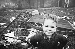 Bedstead: Young boy in front of pile of discarded rubbish