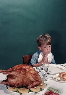 Eyeing: Young boy sitting at dinner table eyeing turkey