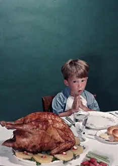 Eyeing: Young boy sitting at dinner table eyeing turkey