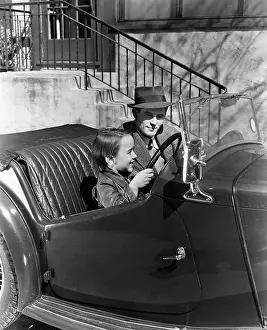 Imitating: Young boy sitting in the driver's seat of car with