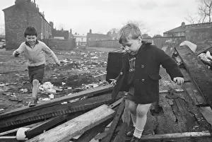 Two young boys playing on pile of discarded rubbish