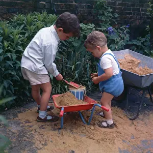 Wheelbarrows: Two young boys playing with sand and their wheelbarrows