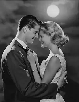 Foreheads: Young couple holding each other close with moon behind them