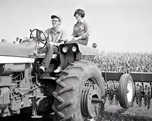 Cultivator: Young Farm Couple riding on a Tractor pulling Cultivator