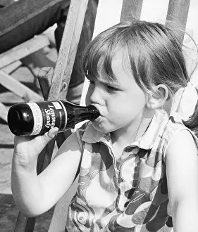Deckchair: Young girl drinking bottle of lemonade shandy