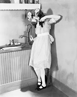 Timid: Young girl gets a sip of pump water in the kitchen
