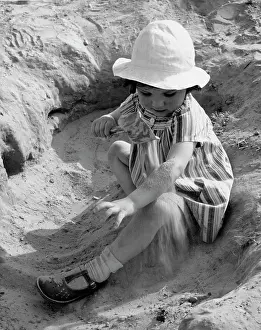 Fascinated: Young girl playing in sand