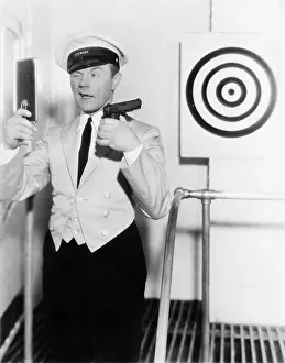 Perseverance: Young man looking at a mirror and aiming at a dartboard