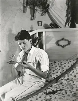 Mends: A young man mends his bow and arrow -