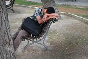 Menorca: A young man sits on a park bench in Mahon, Menorca, Spain