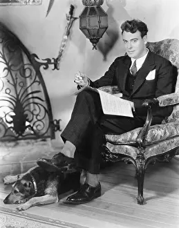 Everett Collection (old Visuals): Young man sitting in an armchair next to a fire