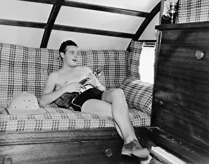Carefree: Young man sitting on a couch and playing a guitar