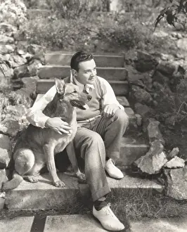 Obedient: Young man sitting with dog on steps outdoors