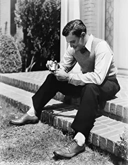 Ponder: Young man sitting on a step and holding a cigarette