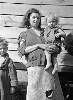 Shoeless: Young mother dressed in a ragged sweater ?