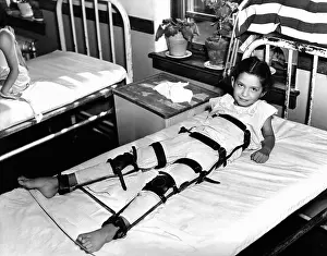 Infantile: Young Polio victim in bed with a body and ?