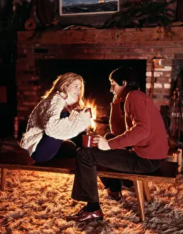Hygge: Young Smiling Couple Sitting by Fireplace