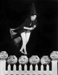 Pumpkins: Young witch hovers on her broom, eyeing which pumpkin