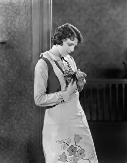 Mournful: Young woman in an apron holding herbs