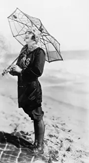 Chuckling: Young woman on the beach with an umbrella looking