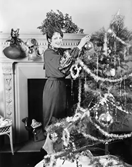 Adorn: Young woman decorating a Christmas tree