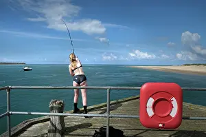 Lifebelt: A young woman fishes from the pier at Aberdovey (Aberdyfi)