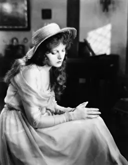 Lamenting: Young woman in a hat sitting and looking sad