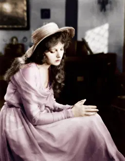 Daydreaming: Young woman in a hat sitting and looking sad