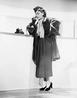 Seriousness: Young woman leaning on a counter and talking on