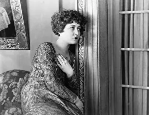 Lamenting: Young woman leaning against the wall, looking sad