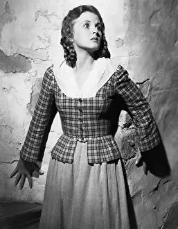 Timid: Young woman leaning against a wall and looking scared
