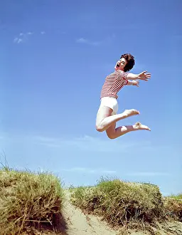 Ecstatic: Young woman leaps up from a sand dune