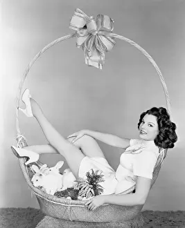 Oversize: Young woman, looking like a present, sitting in