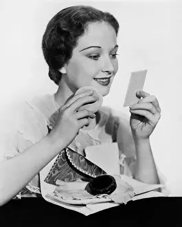 Poise: Young woman looking into a mirror and putting on make up