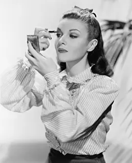 Poise: Young woman looking into a mirror and putting on make up