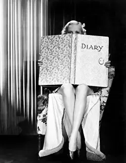 Peaking: Young woman looking over top of an oversized book