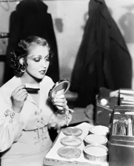 Waist Up: Young woman with a make up brush looking at her