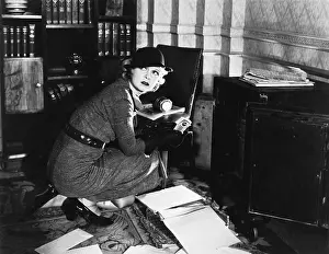 Currencies: Young woman in an office next to a safe, looking