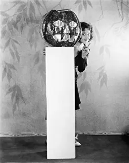 Timid: Young woman peeking from a behind of a Jack O Lantern