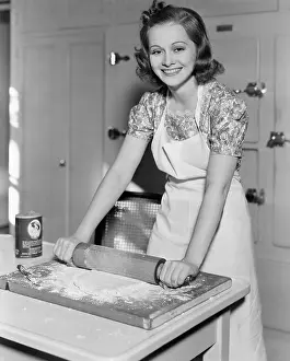 Employ: Young woman rolling out dough in the kitchen