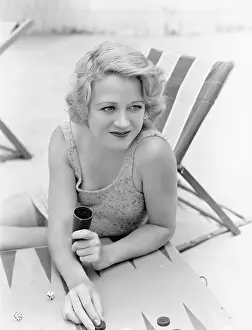 Backgammon: Young woman sitting at the beach playing backgammon