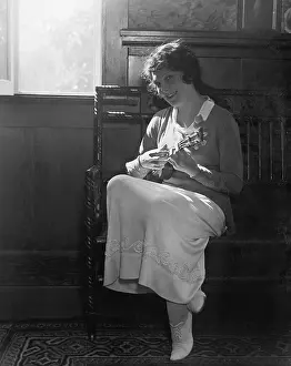 Long Haired: Young woman sitting on a bench playing the mandolin