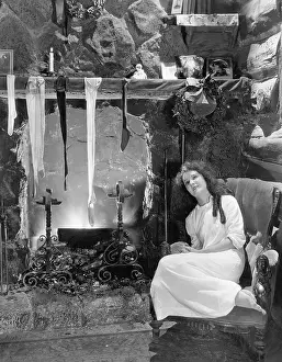 Wistful: Young woman sitting in front of a fireplace, drying