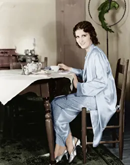 Sustenance: Young woman sitting at a table having breakfast tea