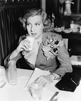 Ruffled: Young woman sitting at a table in a restaurant drinking
