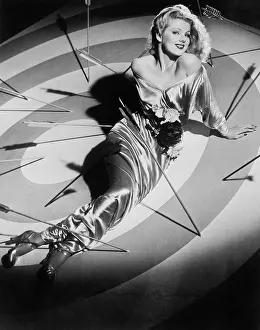 Seducing: Young woman sitting on a target with arrows around her