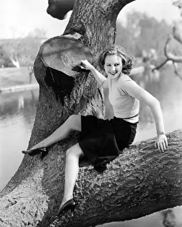 Tomboy: Young woman sitting in a tree writing on tree trunk