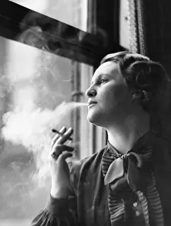 Addicted: Young woman sitting next to window, smoking