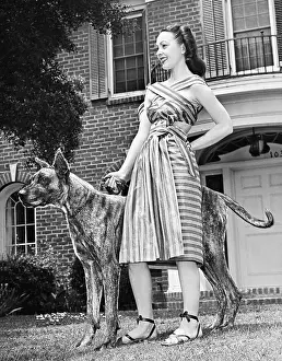 Carefree: Young woman standing with her Great Dane in a courtyard