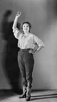 Enjoyable: Young woman standing with her hand raised and smiling